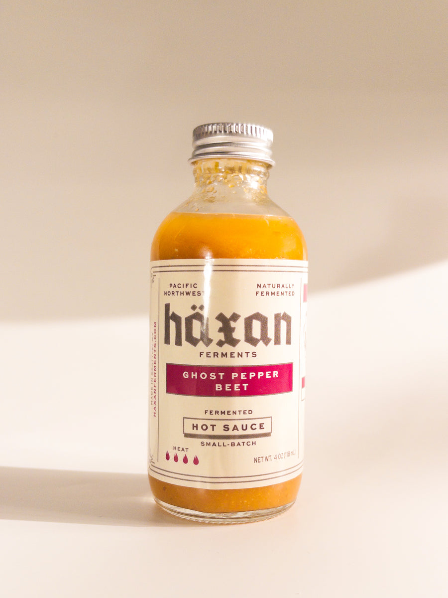 Bottle of häxan Ghost Pepper Beet Hot Sauce on a beige background